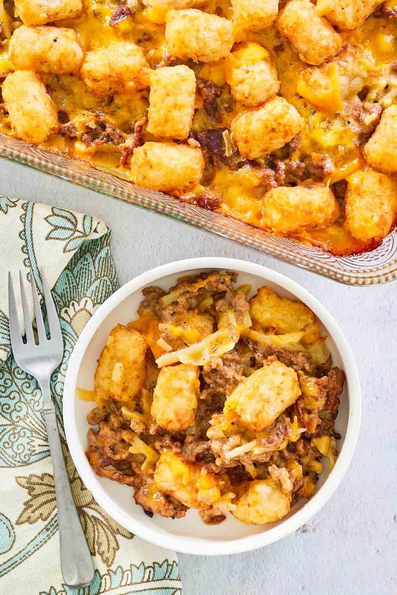 overhead view of hamburger hashbrown casserole in a baking dish and bowl.