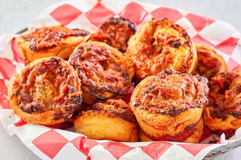 homemade pizza rolls in a bread basket lined with parchment paper.