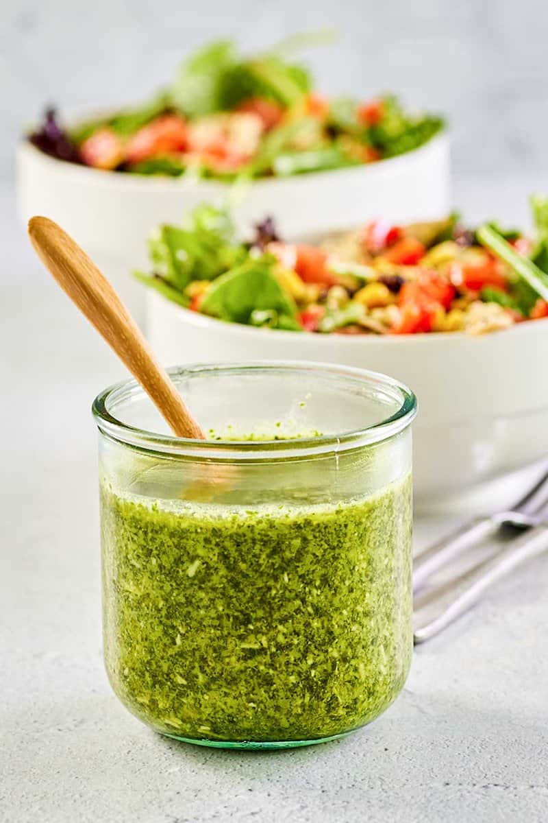 a jar of copycat Cheesecake Factory Santa Fe dressing in front of two salads.