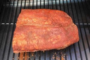 dry rubbed pork belly on a smoker grate.