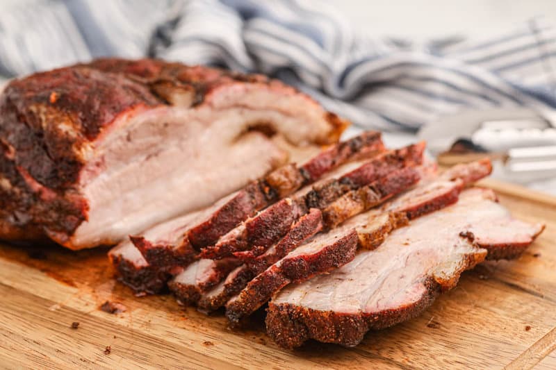 smoked pork belly sliced on a cutting board.