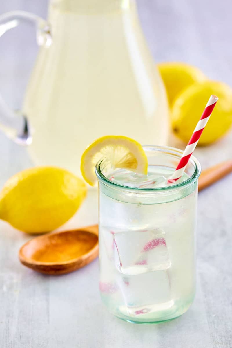 copycat Chick fil A lemonade in a glass and pitcher and fresh lemons.