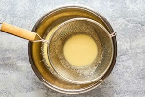 straining French toast batter into a bowl.