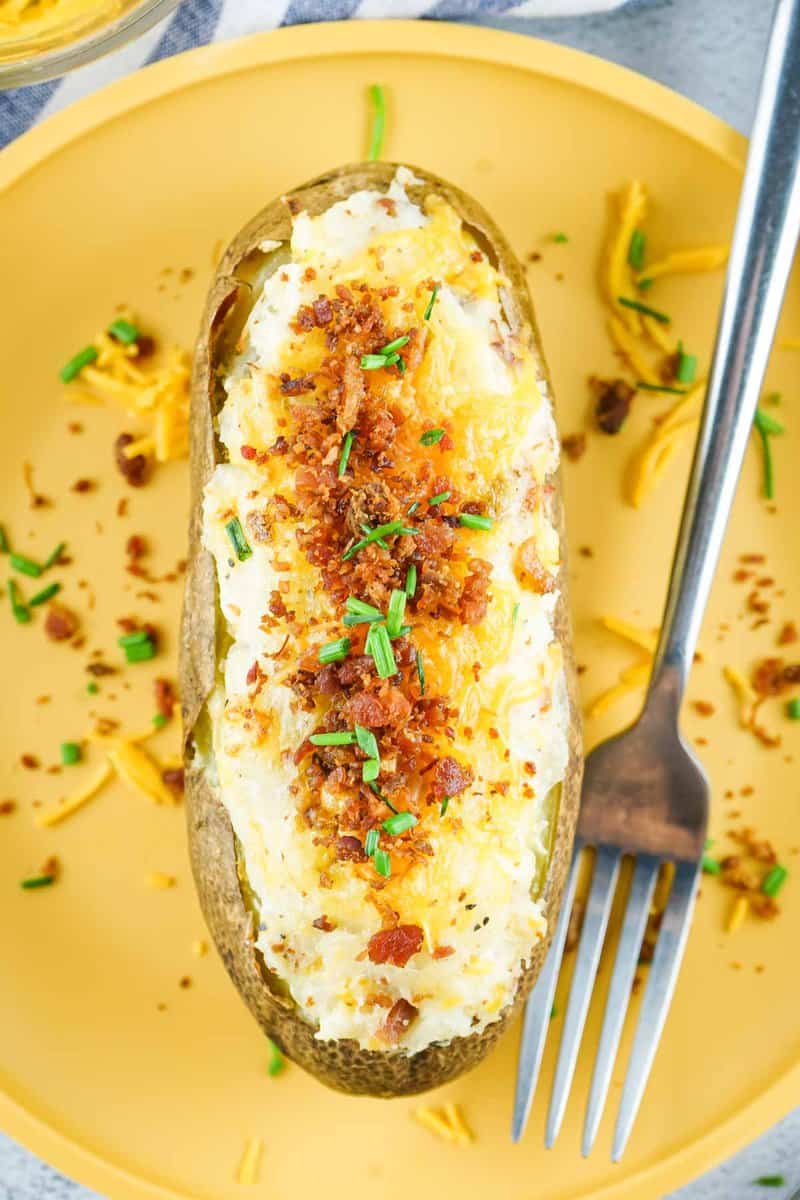 overhead view of a loaded twice baked potato and a fork on a plate.