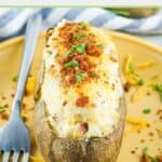 loaded twice baked potato and a fork on a plate.