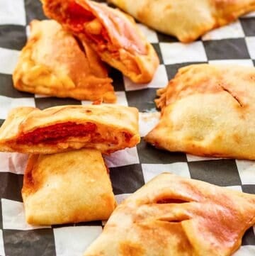 homemade pepperoni hot pockets scattered on parchment paper.