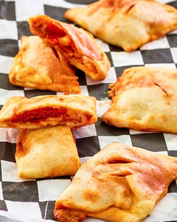 homemade pepperoni hot pockets scattered on parchment paper.