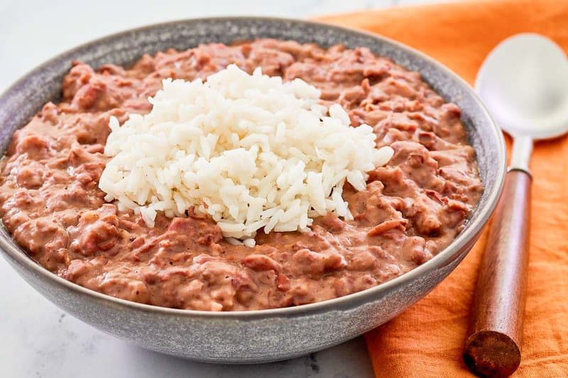 bowl of copycat Popeyes red beans and rice and a spoon on a napkin.