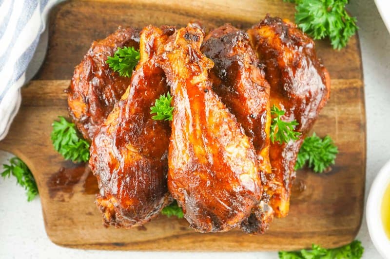 smoked bbq chicken thigs piled on a wood board.