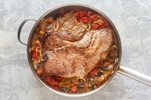 browned beef roast and vegetables in a pan.