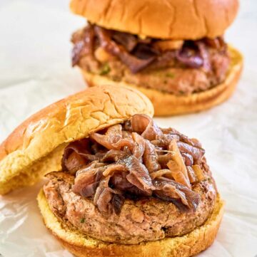 two turkey burgers with caramelized onions and whole grain buns.