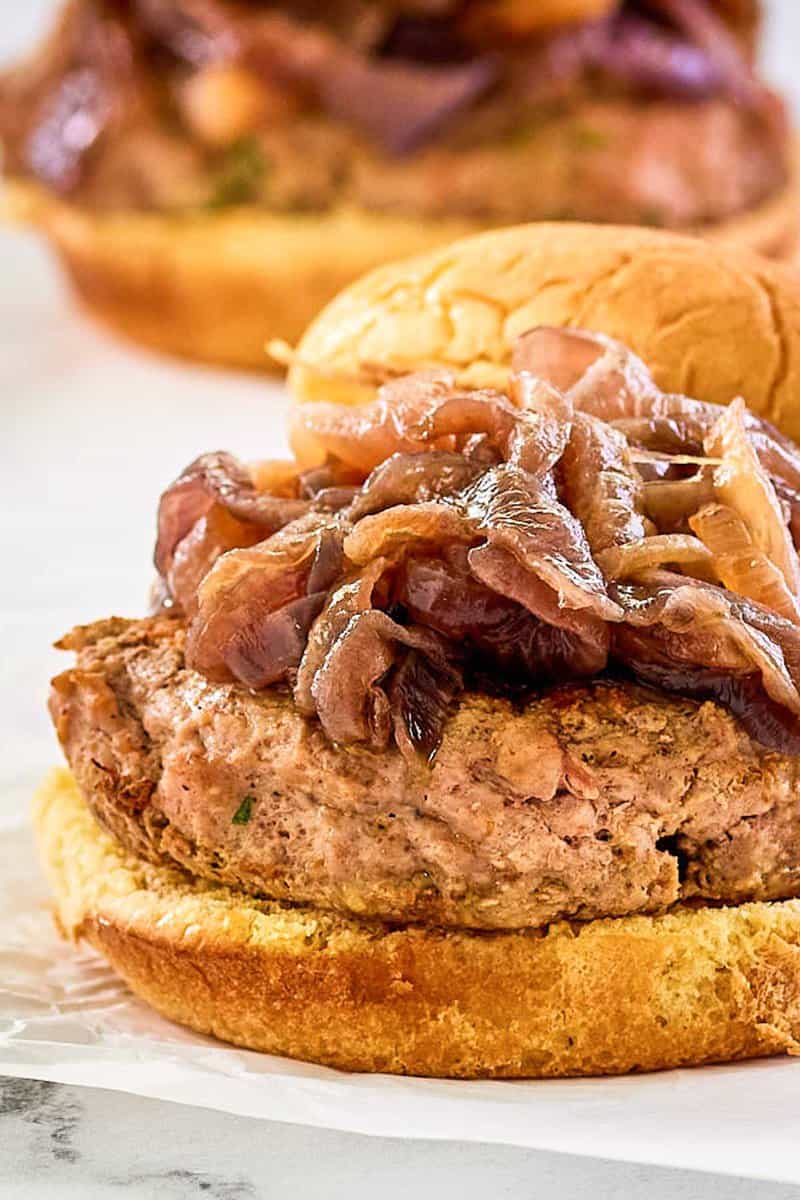 closeup of a turkey burger with caramelized red onions on a wheat bun.