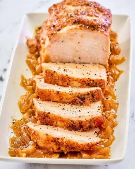 Instant Pot pork loin on top of cooked onions on a platter.