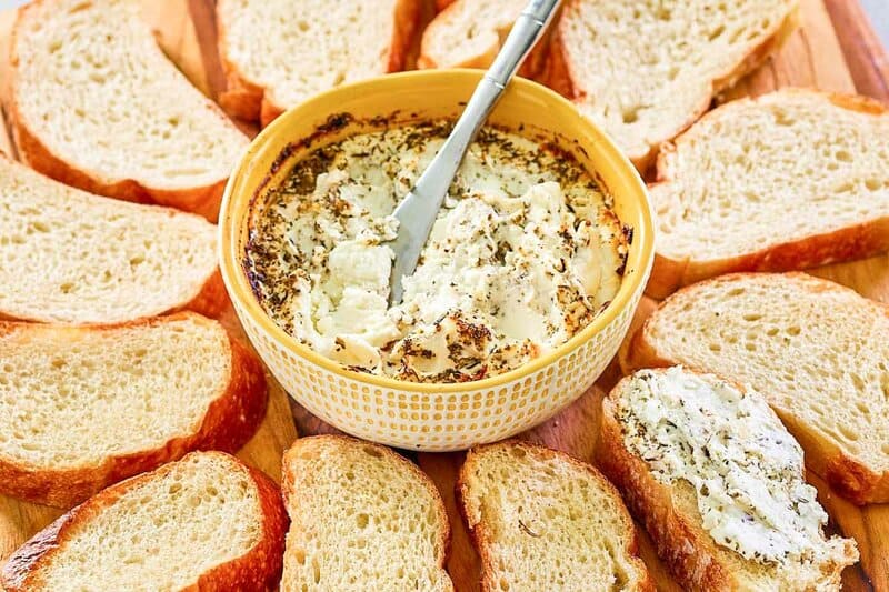 baked goat cheese in a bowl and bread slices around it.