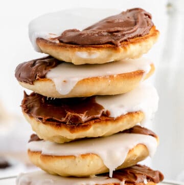 five black and white cookies in a stack on a plate.