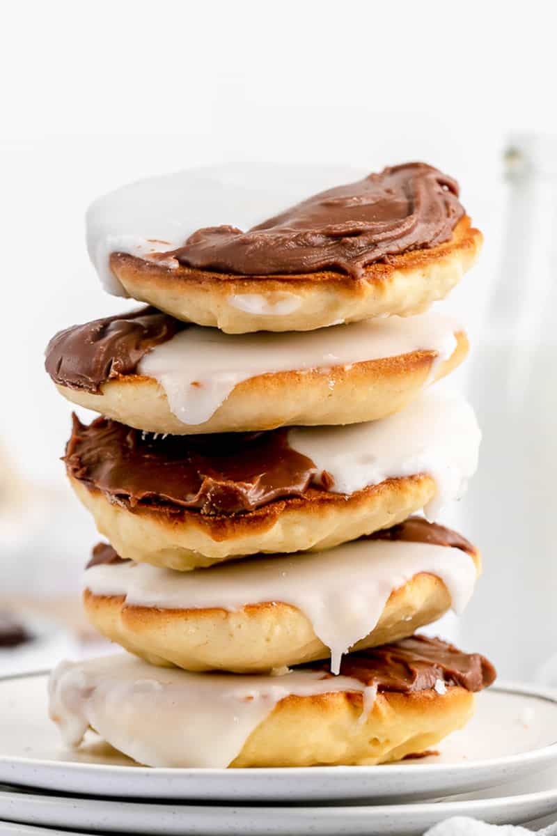five black and white cookies in a stack on a plate.