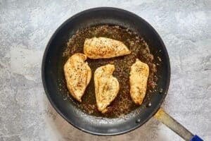 cooked seasoned chicken breasts in a skillet.