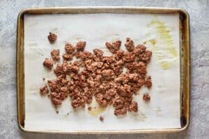 cooked ground beef crumples on a tray.