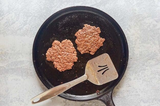 cooked hamburger patties on a griddle.