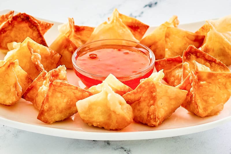 copycat Panda Express cream cheese rangoon on a plate with dipping sauce.