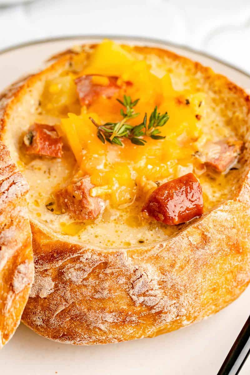 sausage stew topped with cheddar cheese in a bread bowl.