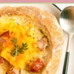 smoked sausage stew topped with cheese in a bread bowl.