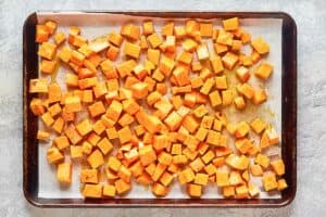 sweet potato cubes coated with honey on a baking sheet.