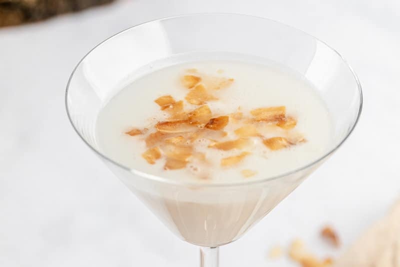 copycat Tommy Bahama coconut cloud martini topped with toasted coconut flakes.