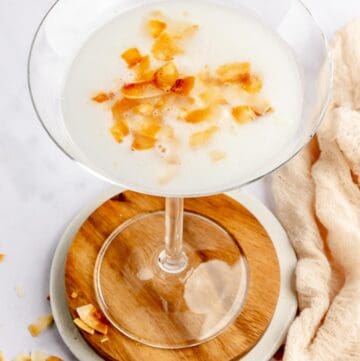 copycat Tommy Bahama coconut cloud martini garnished with toasted coconut flakes.