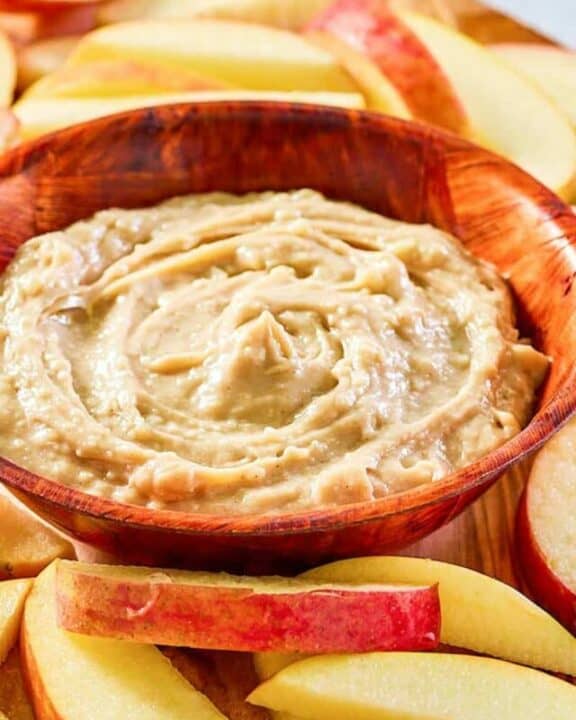 caramel apple dip in a bowl and apple slices around it.