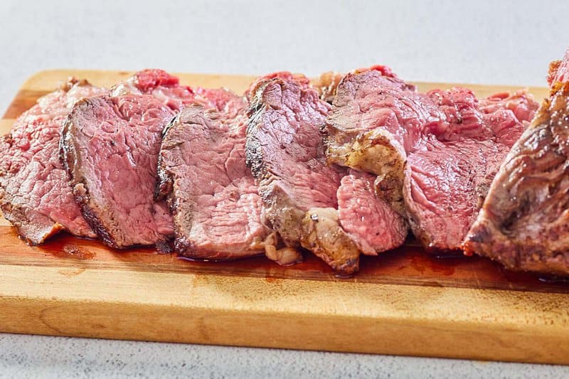 beef tenderloin roast slices on a wood cutting board.