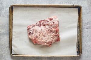 beef tenderloin roast on a parchment paper lined baking sheet.