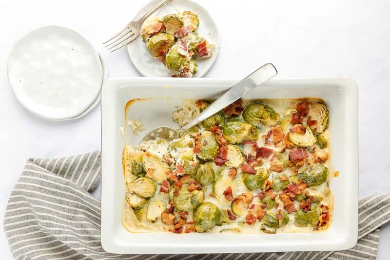 Brussels sprouts au gratin in a baking dish and a serving on a plate.