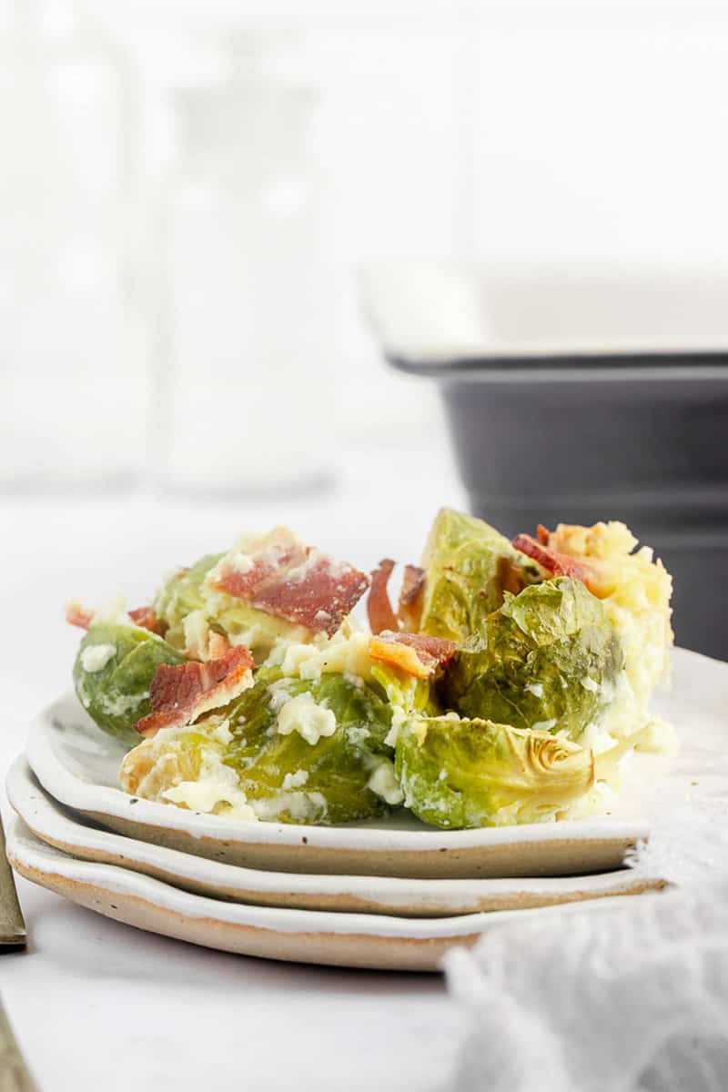 Brussels sprouts au gratin serving on a stack of plates.