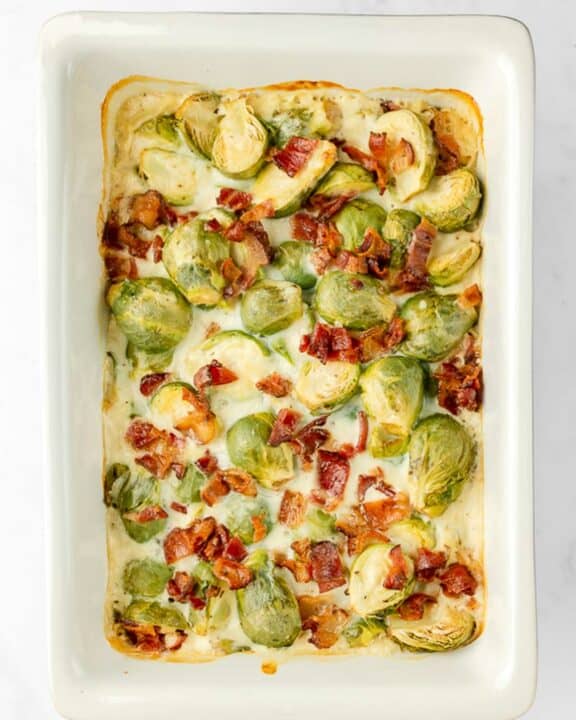 overhead view of Brussels sprouts au gratin with bacon in a baking dish.