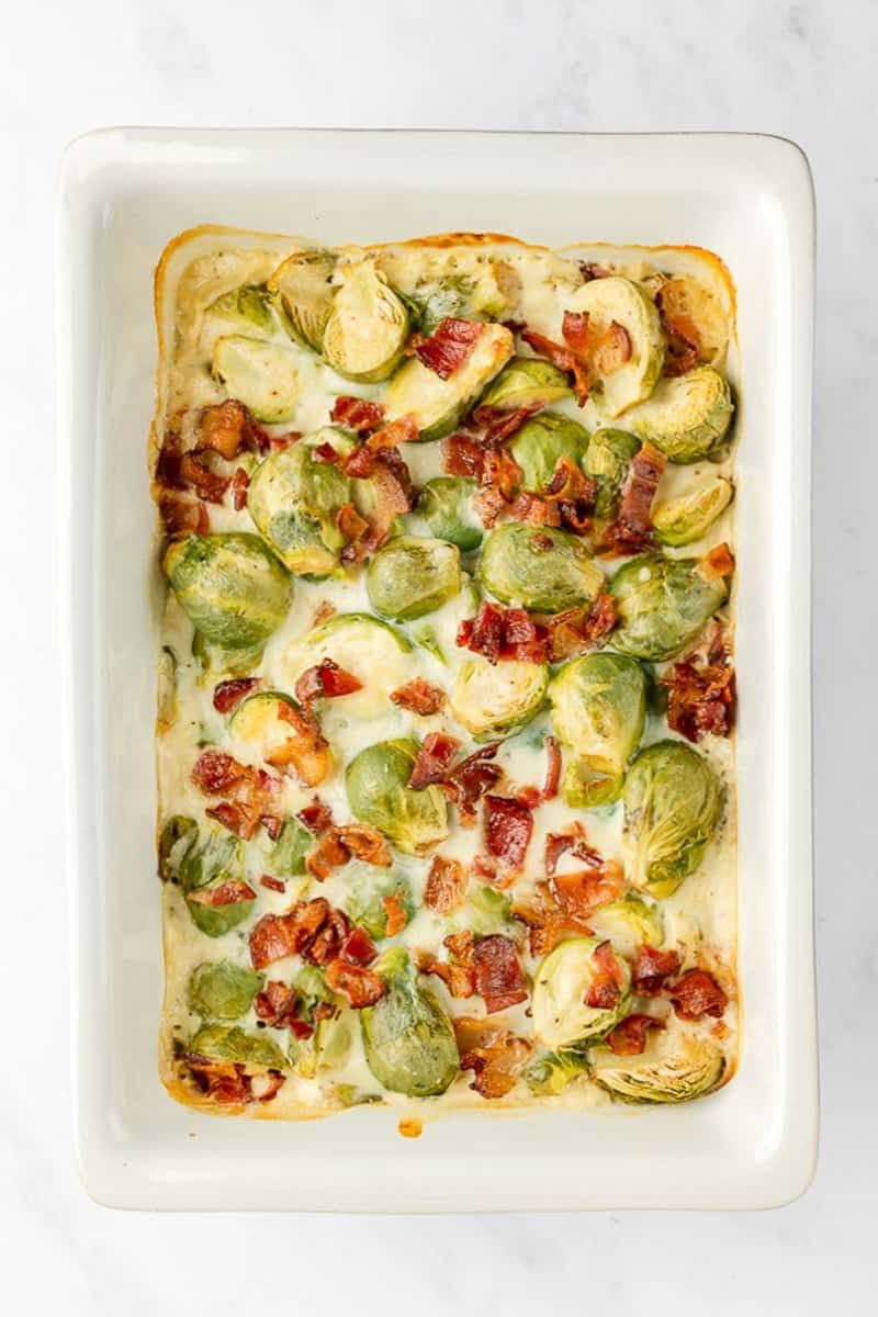 overhead view of Brussels sprouts au gratin with bacon in a baking dish.