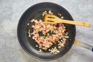 cooked bacon and onions in a skillet.