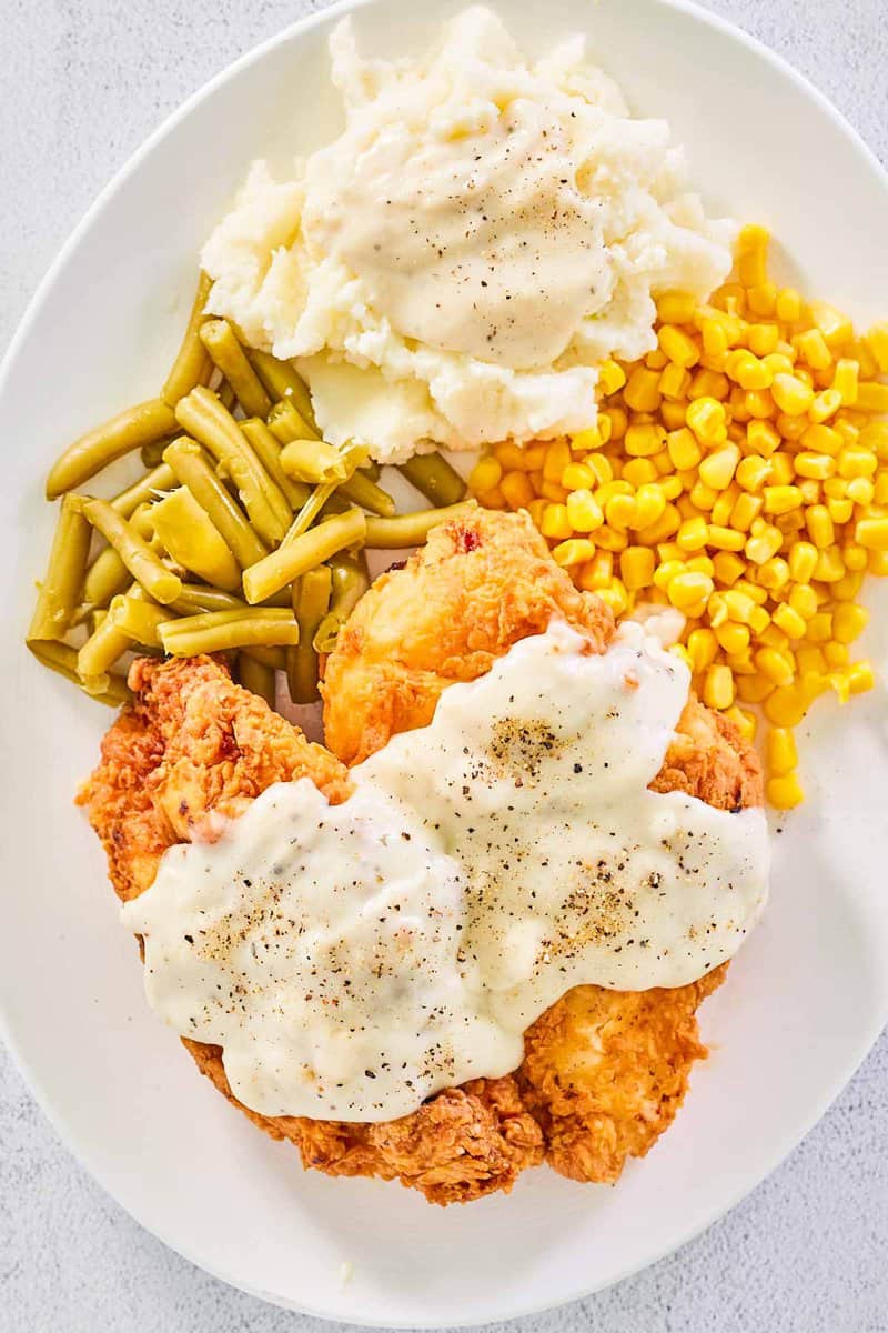 overhead view of copycat Cracker barrel chicken fried chicken with sawmill gravy and vegetables.