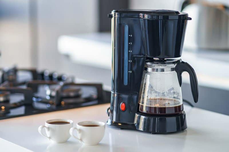 drip coffee maker and two cups of coffee.