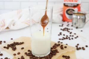adding caramel syrup to a glass with milk.