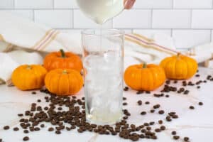 pouring vanilla syrup into a glass with ice.