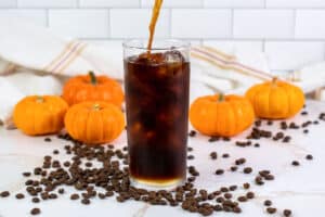 pouring cold brew coffee into a glass with ice.