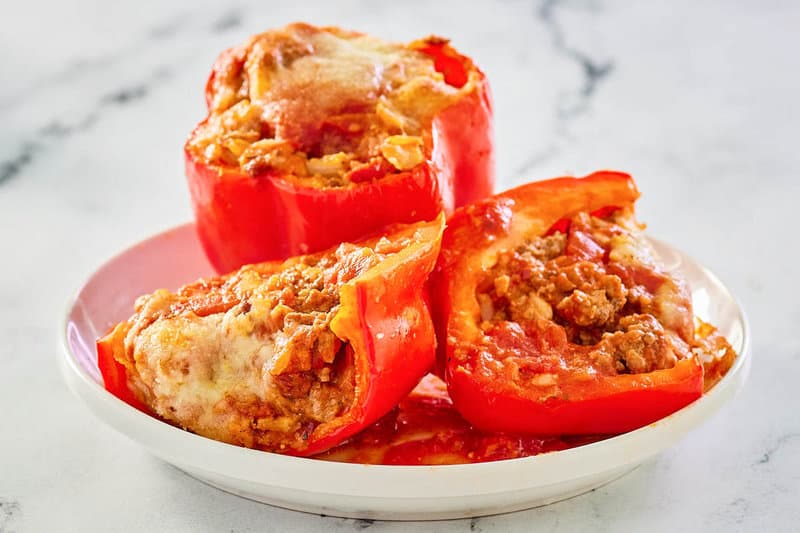 stuffed bell peppers with rice and meat on a white plate.