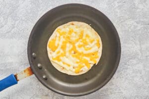 melted cheeses on a flour tortilla in a skillet.