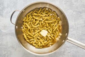 canned green beans and butter in a pan.