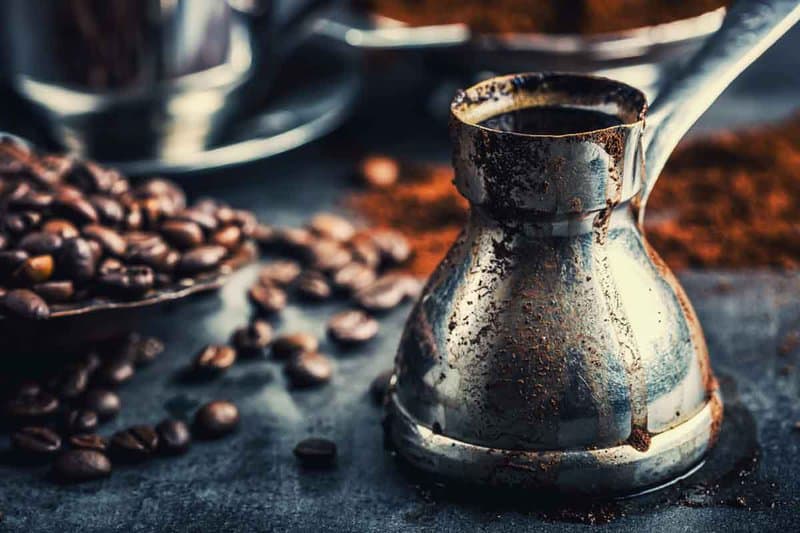 Turkish coffee in a cezve and coffee beans.