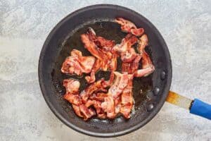 cooked applewood bacon in a frying pan.