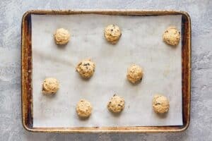 white chocolate cranberry cookie dough balls on a baking sheet.