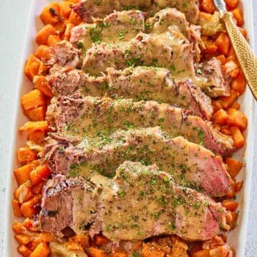 sliced Yankee pot roast with gravy and vegetables on a platter.