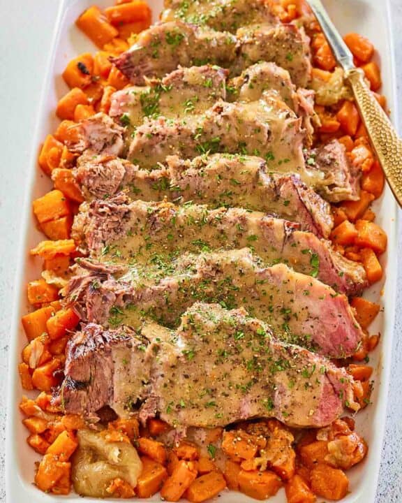 sliced Yankee pot roast with gravy and vegetables on a platter.
